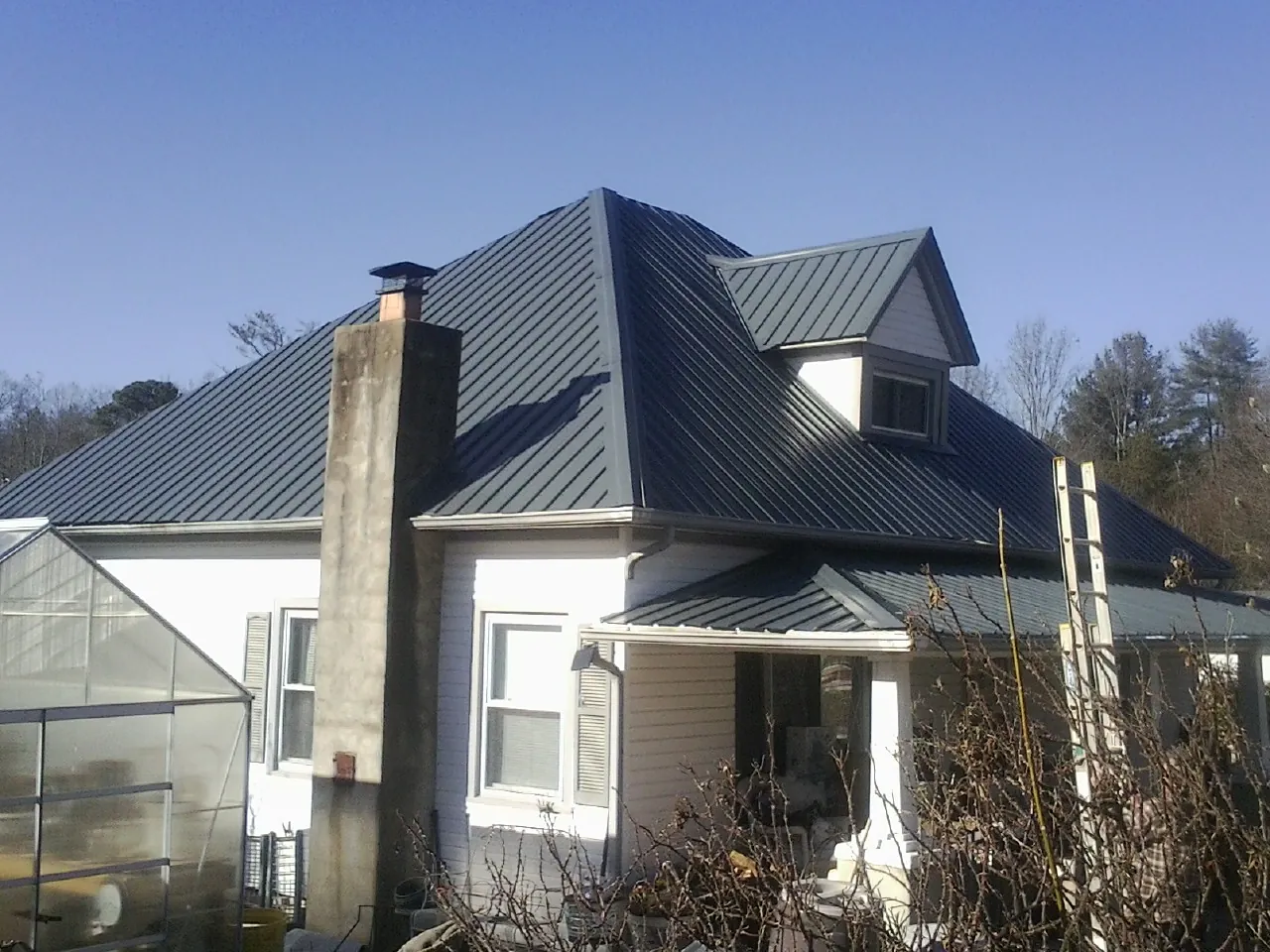 Dark blue standing seam metal roof on a white farmhouse with dormer — Slate & Tile Roof Repair by Roofing Brothers in Buhl