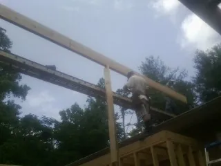 Carpenter setting a ridge beam over a new addition frame — Ice Dam Removal by Roofing Brothers in Buhl