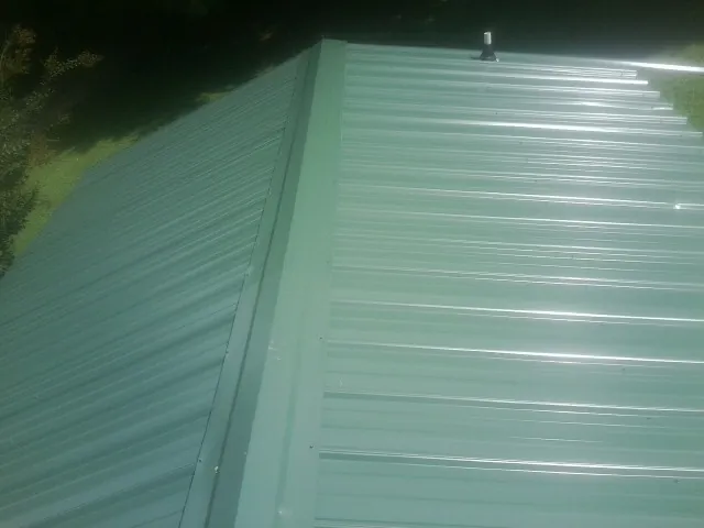 New green metal panels meeting at the ridge of a roof — Flat Roof Repair work by our crew in Buhl