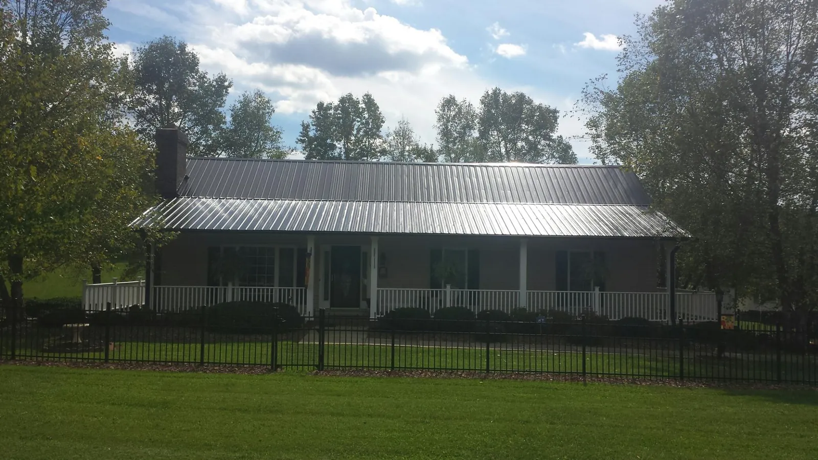 Gray metal roof on a brick ranch with a full width front porch — Gutter Guard Installation work by our crew in Buhl