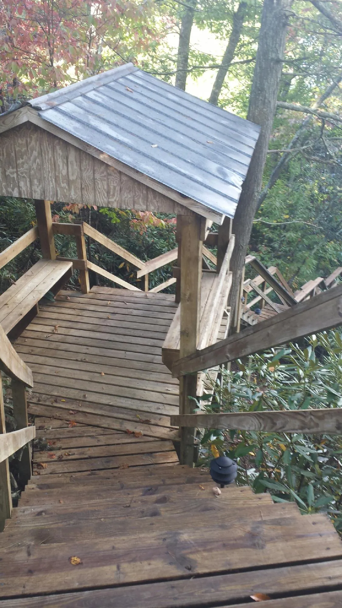 Metal roofed shelter over wooden steps on a wooded walkway — Skylight Repair & Installation work by our crew in Buhl