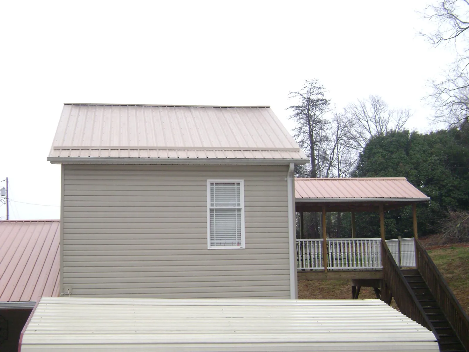 Tan metal roofs on a two story addition and attached porch, from a Roof Replacement job in Buhl